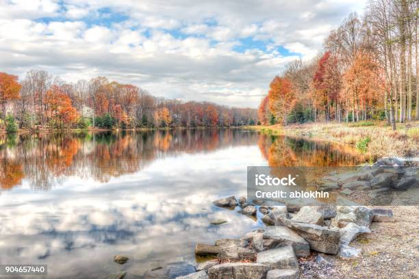 Sunset At Lake Woodglen In Fairfax Virginia Near Residential Neighborhood With Orange Foliage Autumn Trees Forest Water Reflection Houses Rocky Beach Shore Stock Photo - Download Image Now