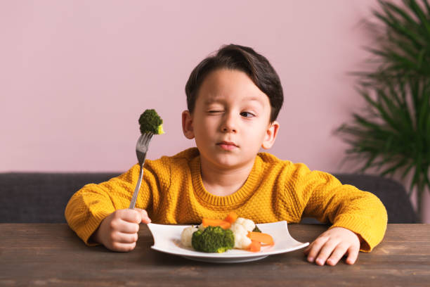 子供が野菜を食べることに非常に満足ではないです。 - cute disgust carrot caucasian ストックフォトと画像