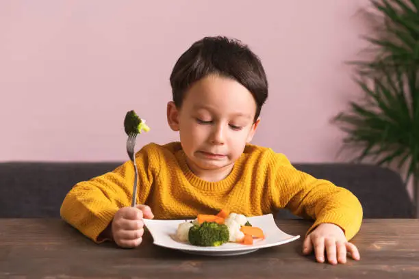 Child is very unhappy with having to eat vegetables. There is a lot of vegetables on his plate. He hates vegetables.