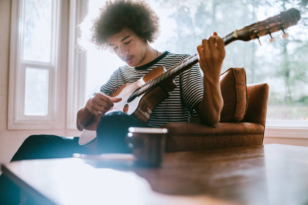 istock Young Man Playing Guitar in Living Home 904661172