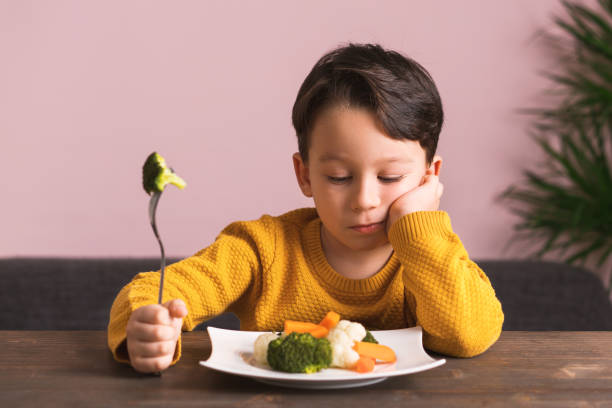 dziecko jest bardzo niezadowolone z konieczności jedzenia warzyw. - cute disgust carrot caucasian zdjęcia i obrazy z banku zdjęć