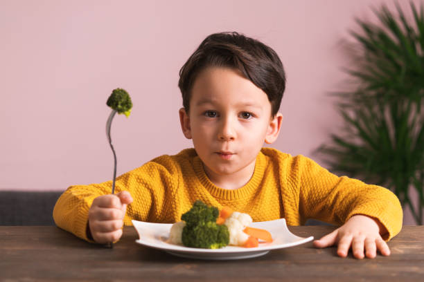 子供が野菜を食べることに非常に満足ではないです。 - cute disgust carrot caucasian ストックフォトと画像