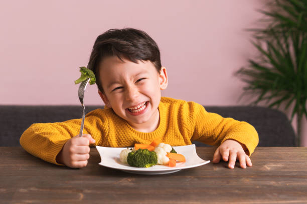 il bambino sta mangiando verdure. - food healthy eating carrot table foto e immagini stock
