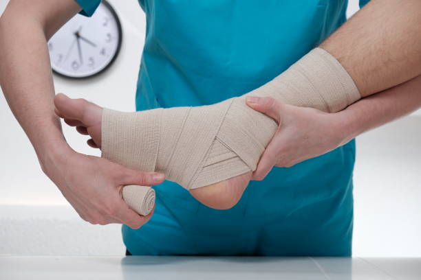 Close-up of male doctor bandaging foot of female patient stock photo