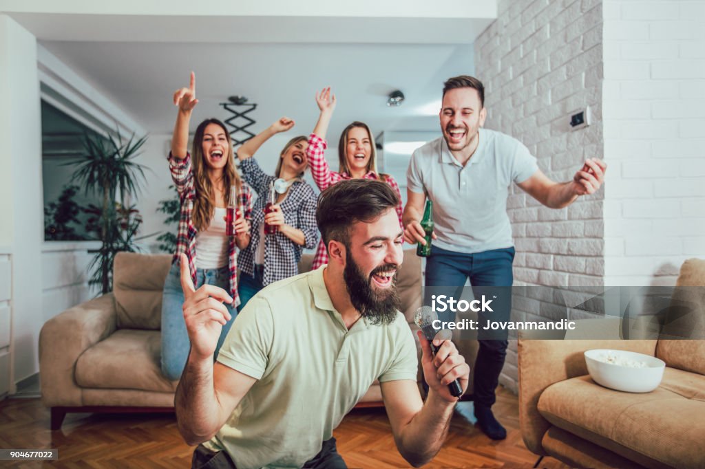 Group of friends playing karaoke at home Group of friends playing karaoke at home. Concept about friendship, home entertainment and people Friendship Stock Photo