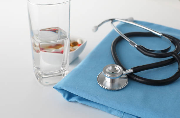 istock stethoscope a glass of water and pills on a uniform 904677064