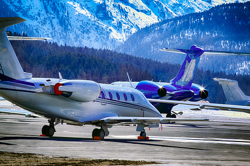 Private jets, planes and helicopters in the beautiful snow covered mountains of alps in St Moritz Switzerland