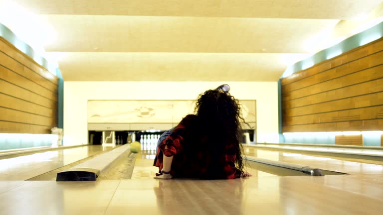 Young woman falls down while throws a bowling ball