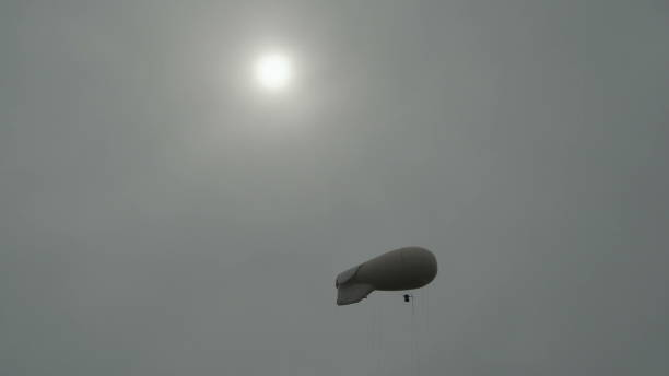 飛艇飛艇齊柏林氣體氦漂浮在天空在太陽背景下的灰色傍晚天空觀察環境, 並作出氣象觀測 - spy balloon 個照片及圖片檔