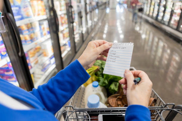 Point of view of woman using shopping list in grocery store This photograph was taken from the point of view of a woman walking down the frozen foods section of a grocery store and searching for items using a shopping list. shopping list stock pictures, royalty-free photos & images