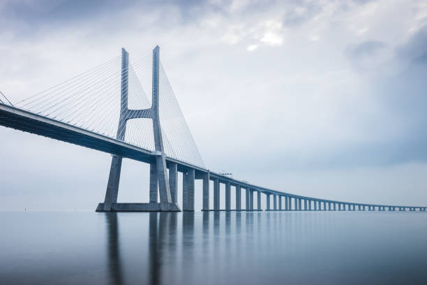 мост васко да гама на рассвете в лиссабоне, португалия. он самый длинный мост в европе - bridge crossing cloud built structure стоковые фото и изображения