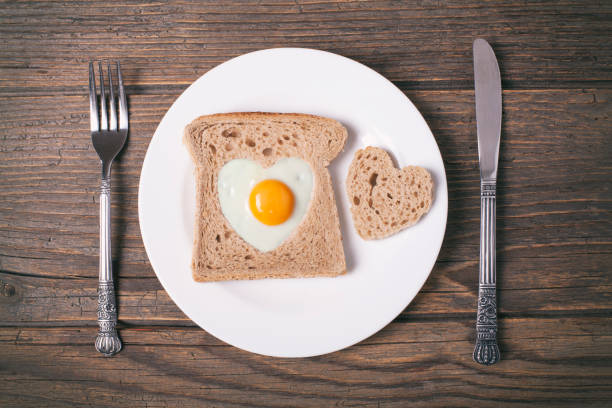 istock Egg fried in heart-shaped toast cutout on rustic wooden table. 904721552