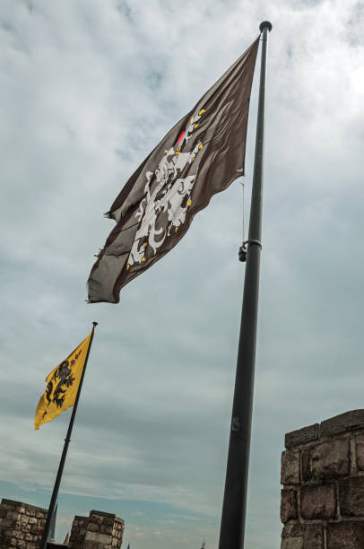 bandeiras e céu nublado, visto no topo da torre de gravensteen castelo em ghent. - flag flanders medieval lion - fotografias e filmes do acervo