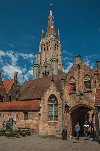 Bruges, Belgium - July 05, 2017. Brick facade of houses, people and blue sky in a peaceful courtyard in Bruges. With many canals and old buildings, this graceful town is a World Heritage Site of Unesco. Northwestern Belgium.