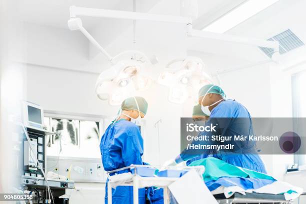 Kirurger Som Arbetar Under Belysningsutrustning-foton och fler bilder på Operationssal - Operationssal, Kirurgi, Kirurg