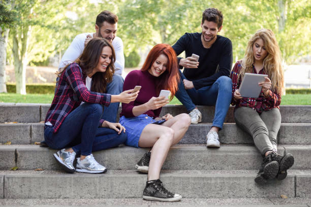 istock Young people using smartphone and tablet computers outdoors 904806124