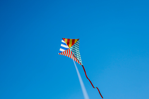 Colorful kite flying with waving red bow