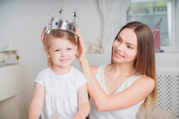 istock mother holding a crown and her daughter 904813656