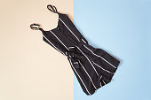 Black striped romper, tender pink and blue background. Fashionable concept