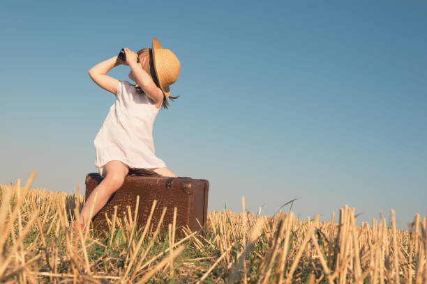 istock Little girl with suitcase is looking trough binoculars 904821304