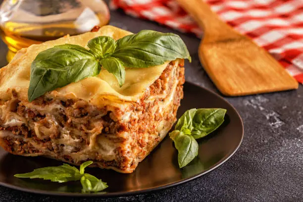Traditional lasagna made with minced beef bolognese sauce and bechamel sauce topped with basil leaves.
