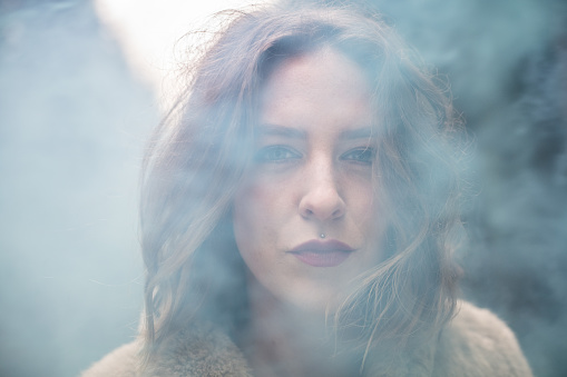 Young woman portrait outdoors in the woods with smoke bombs; Europe.