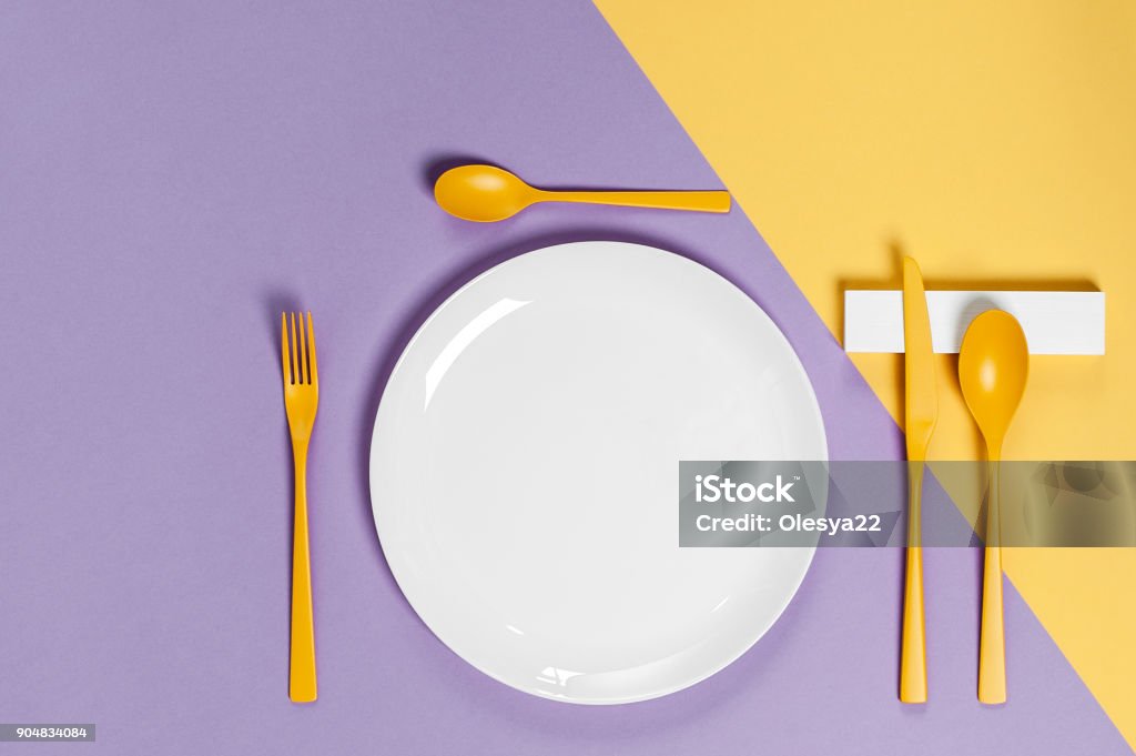 Blanc ustensiles et coutellerie jaune sur un fond de couleur pastel. Couleurs dans le style de la pop. - Photo de Assiette libre de droits