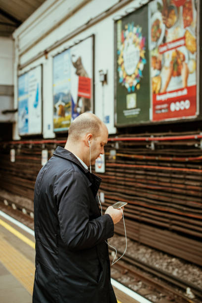 hombre masculina usando iphone smartphone teléfono en tubo de londres subterráneo - macintosh apple fotografías e imágenes de stock