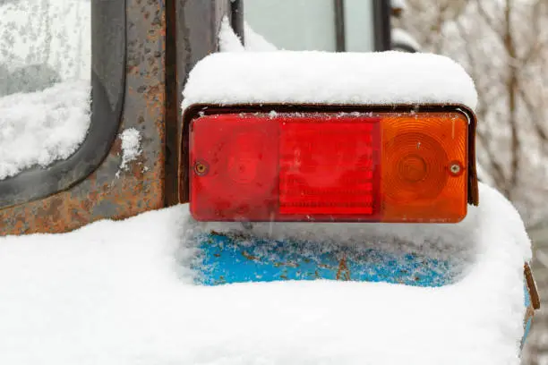 Photo of Old tractor taillight closeup covered with snow in winter
