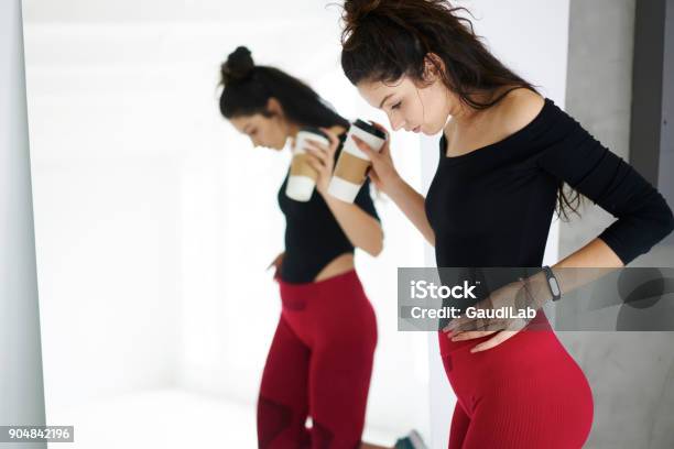 Attractive Brunette Female Checking Results Of Active Healthy Lifestyle After Hard Workout Dressed In Trendy Training Session Slim Girl With Perfect Body Shape Resting On Break Looking At Reflection Stock Photo - Download Image Now