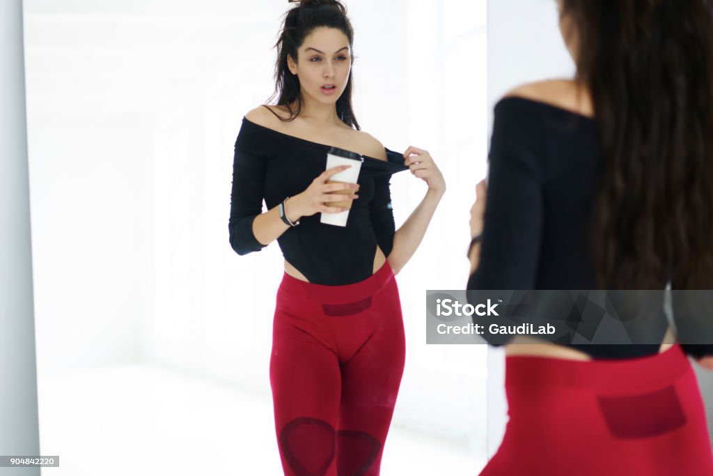 sportswoman with her reflection in mirror resting with beverage after training session in gym, attractive fitness girl  keeping perfect body shape reaching goals and targets slenderize portswoman with her reflection in mirror resting with beverage after training session in gym, attractive fitness girl  keeping perfect body shape reaching goals and targets slenderize Slenderman - Fictional Character Stock Photo