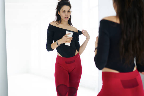 sportswoman with her reflection in mirror resting with beverage after training session in gym, attractive fitness girl  keeping perfect body shape reaching goals and targets slenderize portswoman with her reflection in mirror resting with beverage after training session in gym, attractive fitness girl  keeping perfect body shape reaching goals and targets slenderize slenderman fictional character stock pictures, royalty-free photos & images