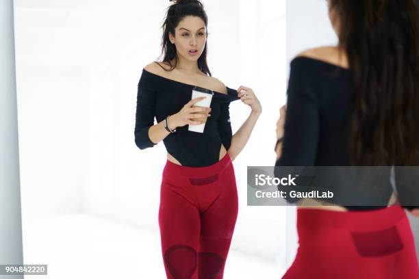 Sportswoman With Her Reflection In Mirror Resting With Beverage After Training Session In Gym Attractive Fitness Girl Keeping Perfect Body Shape Reaching Goals And Targets Slenderize Stock Photo - Download Image Now