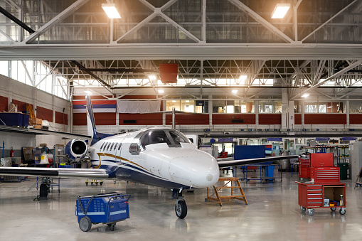Private jet airplane in the hangar ready for maintaining service.