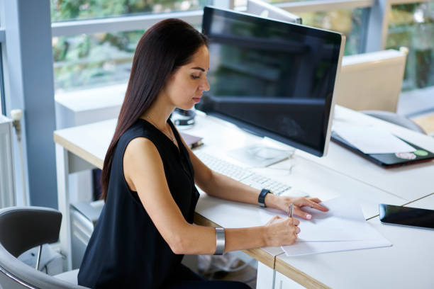 istock Charming female journalist concentrated on creation article for publication writing text on paper, prosperous businesswoman  signing contract with successful trading corporation sitting in office 904848486