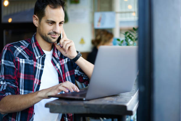 istock Concentrated casually dressed male freelancer having phone conversation about working task while sitting in cafe interior, handsome entrepreneur confirming booking on website contact service on mobile 904852494