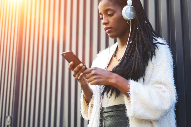 istock Serious afro american hipster girl using application for listening songs from playlist while chatting standing on promotional background, attractive female black model enjoy radio broadcasting 904855552