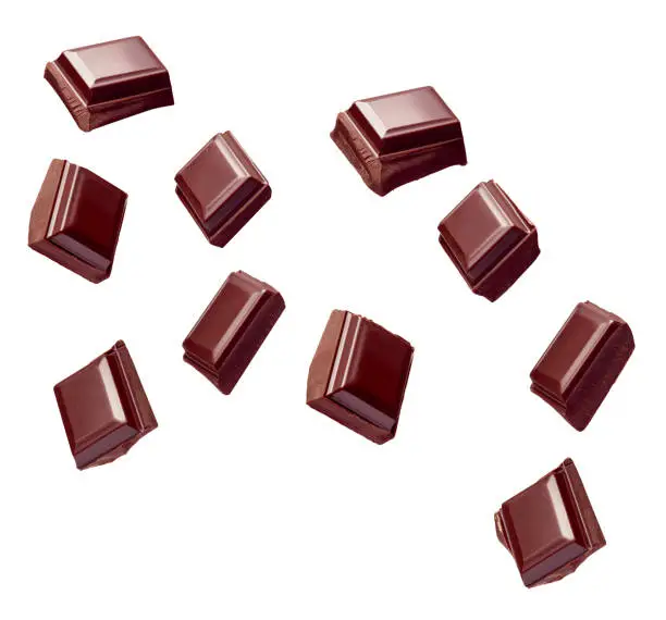 close up of chocolate pieces stack falling on white background