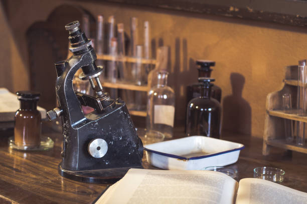 antique laboratory, microscope and glass tubes - book school desk old imagens e fotografias de stock