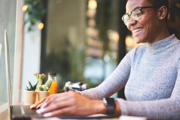 istock Cheerful afro american web designer satisfied with completing project earning money online while sitting in cafe interior near advertising area,smiling female student receiving good job offer on email 904867630