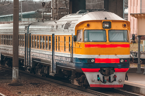 Old yellow passenger diesel train moving at the terminal