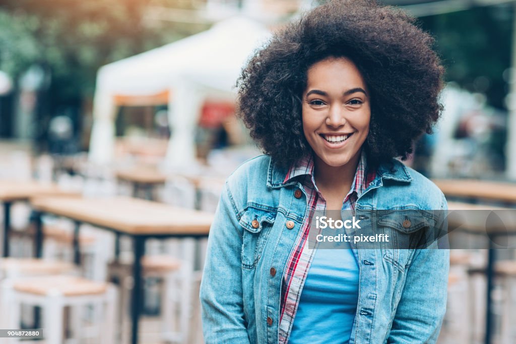 Portrait of a smiling girl outdoors in a sidewalk cafe Young African ethnicity woman outdoors in the city African Ethnicity Stock Photo