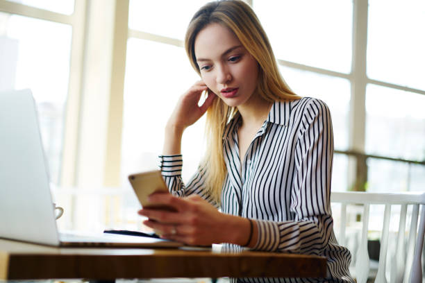 istock Pensive blonde female manager in formal wear checking email box waiting for feedback while working in cafe interior, concentrated young freelancer paying for receipt online receiving notification 904880158