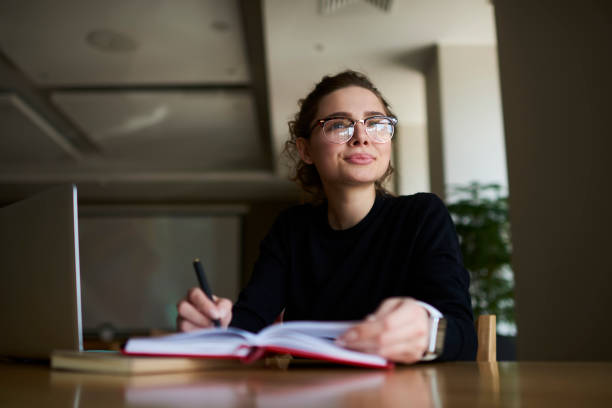 istock Thoughtful skilled businesswoman looking away and thinking about creative ideas for article publication.Young charming hipster girl in good mood dreaming sitting at table with modern laptop 904881132