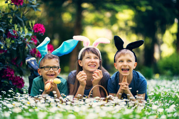 istock Kids with bunny ears playing easter egg hunt in garden 904884098