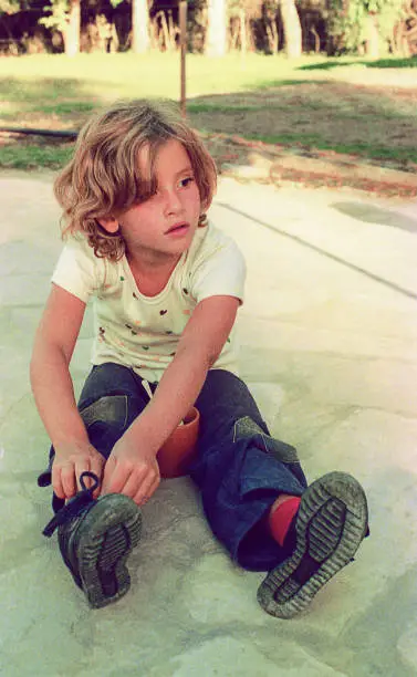 Vintage image from the seventies of a tomboy girl sitting outdoors.