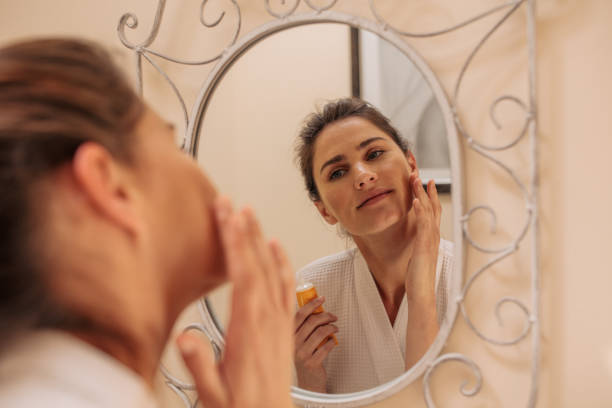 istock Female in mirror applying cream on her face 904892556