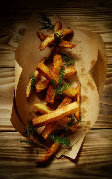 Fried potato country-style in kraft bag on wooden background