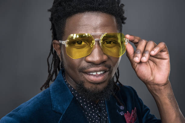 istock man in yellow sunglasses looking at camera isolated on gray 904899036