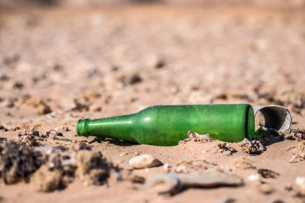 istock old green empty glass bottle on the sand. Macro. 904908752